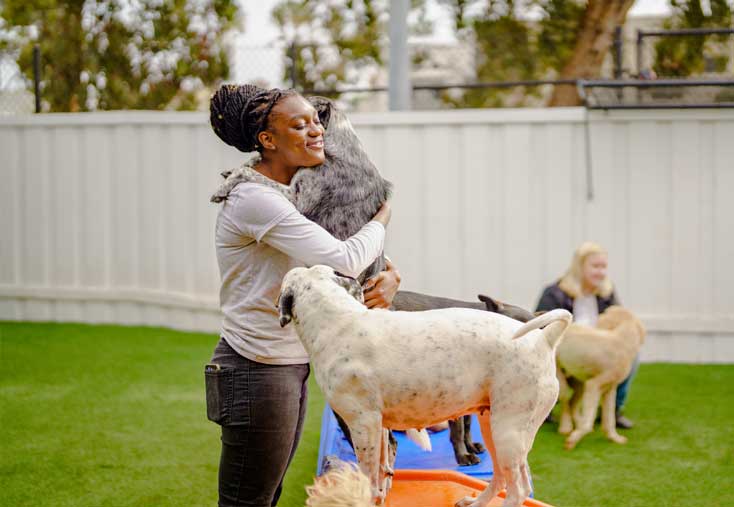 Staff hugging a dog during outdoor play