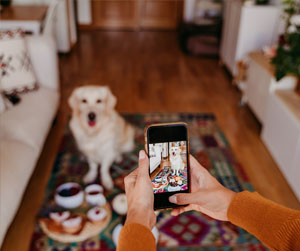 Woman taking a photo of a dog with her phone